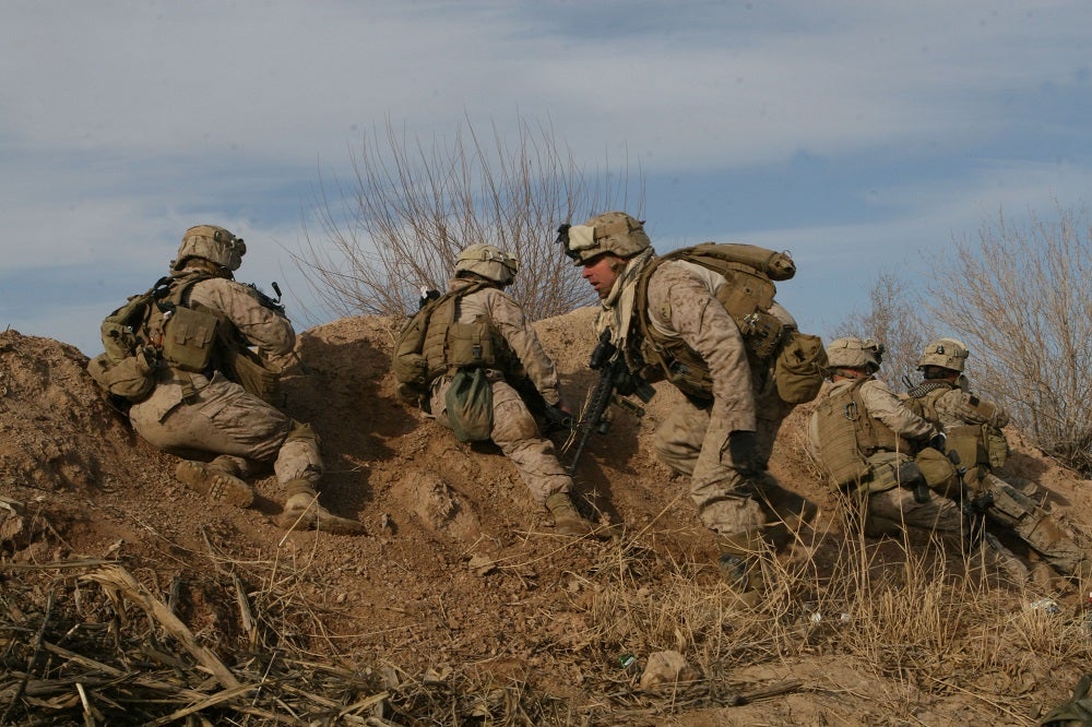 Marines and Afghan National Army soldiers with Bravo Company, 1st Battalion, 6th Marine Regiment take cover behind a berm after recieving accurate small arms fire, Feb. 13, in the city of Marjeh, Afghanistan. Marines with Bravo and Alpha Co., 1/6 were inserted into the city at night by helicopters as part of a large scale offensive aimed at routing the Taliban from their last known stronghold.