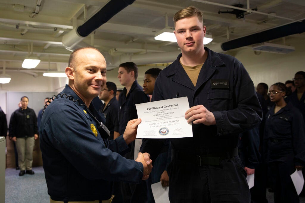 ATLANTIC OCEAN (Dec. 8, 2019) Electrician's Mate Fireman Anthony Christians, from Norwich, Connecticut, assigned to USS Gerald R. FordÕs (CVN 78) engineering department, receives his Navy Security Forces Sentry certificate of graduation presented by Lt. Cmdr. Charles Cranston, FordÕs security officer, during the Security Reaction Force Basic class graduation. Ford is currently underway conducting an independent steaming exercise. (U.S. Navy photo by Mass Communication Specialist Seaman Apprentice Angel Thuy Jaskuloski)
