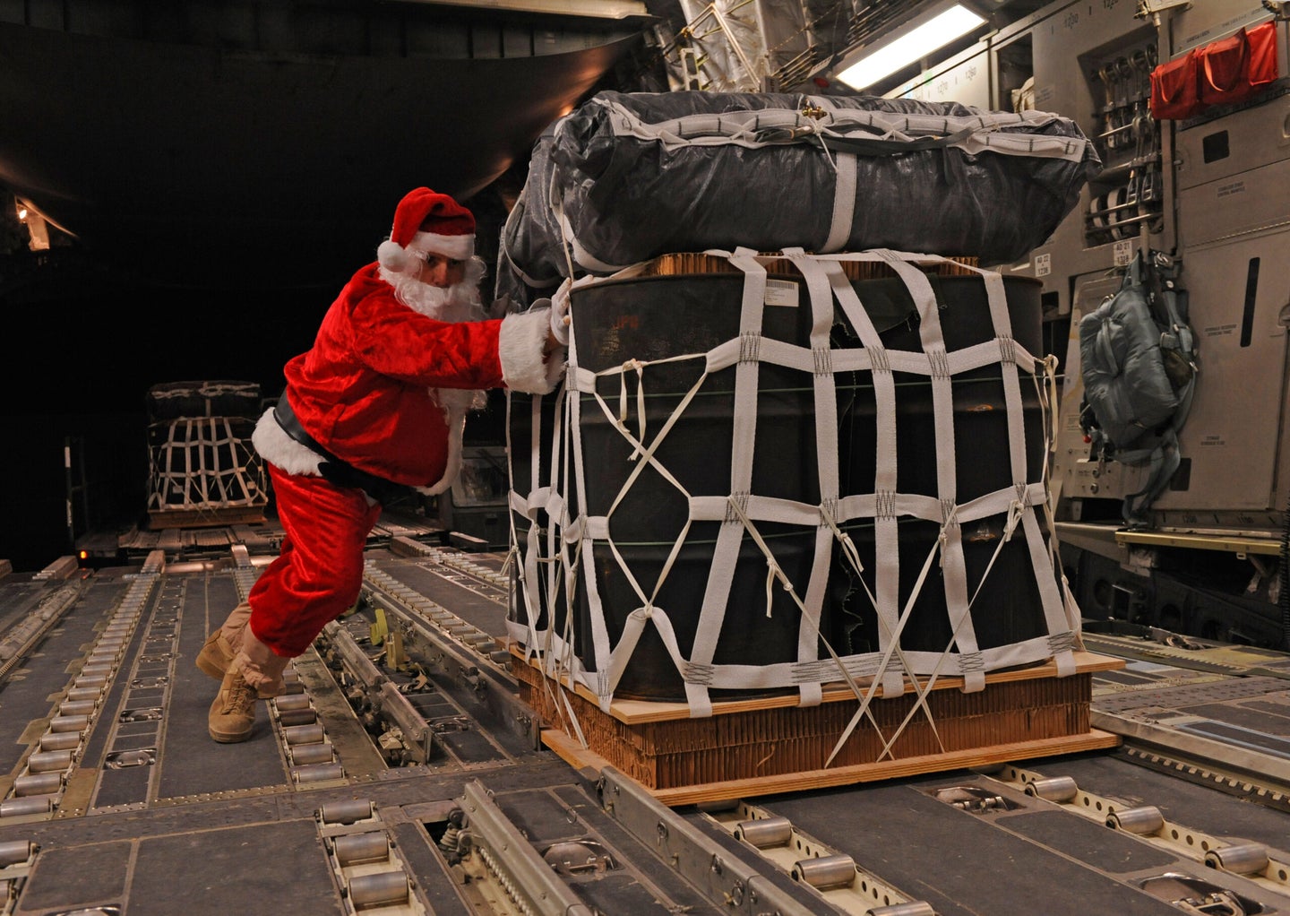 Santa Claus, portrayed by Tech. Sgt. Mike Morris, 816th Expeditionary Airlift Squadron Loadmaster Flight NCO in charge and native of Charleston, S.C., pushes a pallet of fuel onto a C-17 Globemaster III prior to a mission in southwest Asia on Dec. 23, 2011.