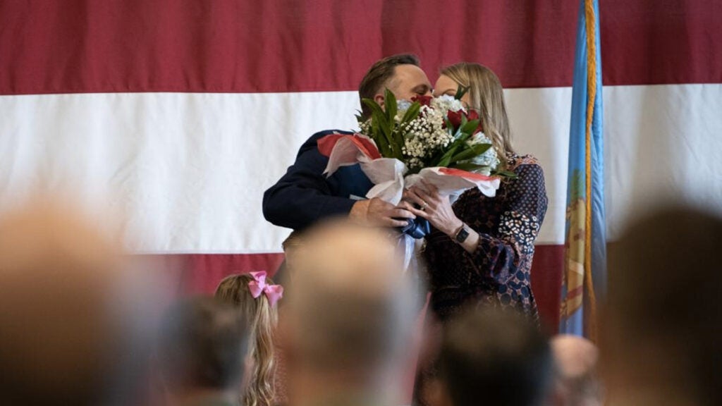 Lt. Col. Mike Coloney, 125th Fighter Squadron director of operations, presents his wife with flowers during a Distinguished Flying Cross Ceremony at the Tulsa Air National Guard Base, Okla., Dec. 5, 2021. The Distinguished Flying Cross is the fourth highest award for heroism and the highest award for extraordinary aerial achievement. (U.S. Air National Guard Photo by A1C Allen Tyler/Released)