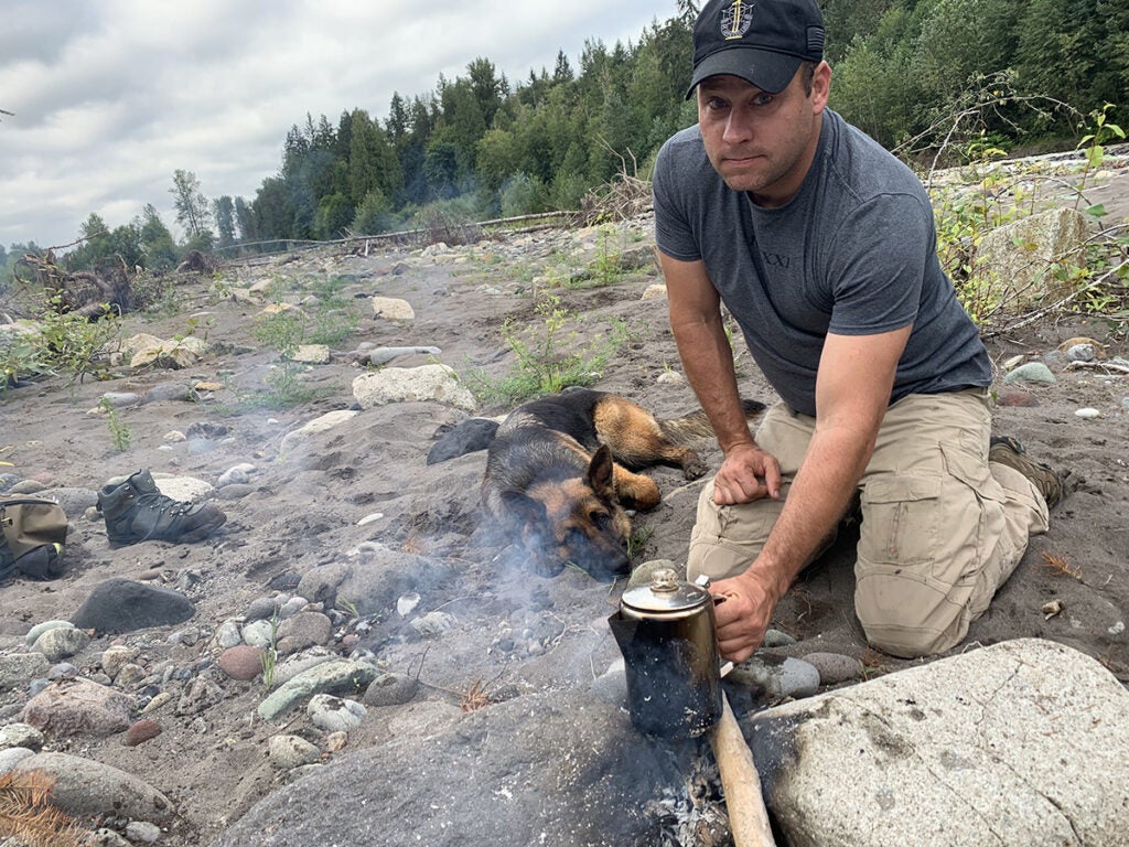Master Sgt. Earl Plumlee makes coffee from a river with his dog Pepper. (Photo Courtesy of Plumlee Family)
