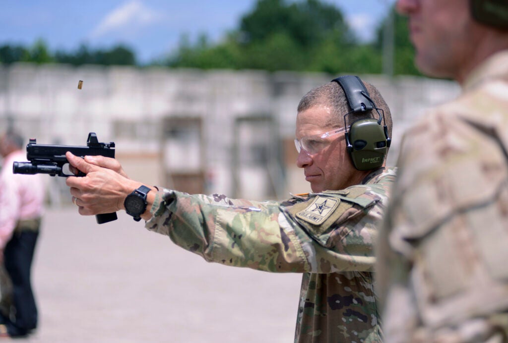 Sergeant Major of the Army Michael A. Grinston, fires a pistol as an instructror from the U. S. Army John F. Kennedy Special Warfare Center and School looks on during a visit to Fort Bragg, North Carolina June 23, 2020. The Sgt. Maj. of the Army spent the day with Soldiers and instructors from Range 37 observing training and taking part firing various weapons on the special operations range. (U.S. Army photo by K. Kassens)