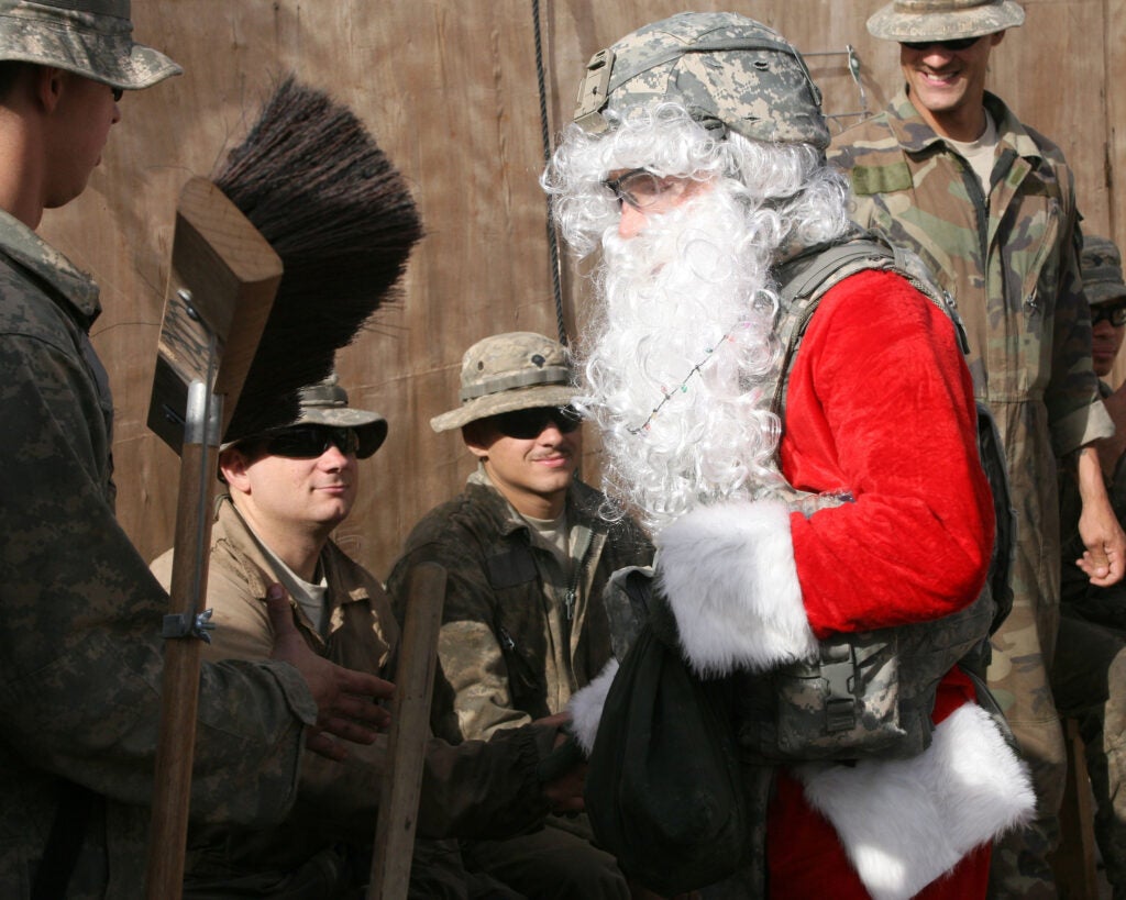 Capt. James Thomas, dressed as Santa, shakes hands with Soldiers in the motor pool of Patrol Base Assassin. Thomas serves with Headquarters and Headquarters Company, 2nd Brigade Combat Team, 1st Armored Division, Multi-National Division - Baghdad. He flew around on Christmas day with Col. Pat White, commander of the Iron Brigade, to lift Soldiers' spirits. Thomas is a native of Oskaloosa, Kan., and White is native of Apple Valley, Calif.