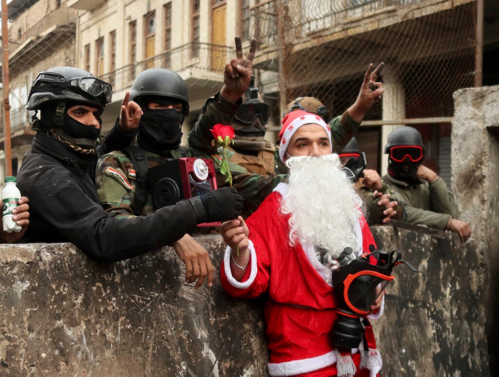 Iraqi security forces take pictures with a protester dressed as Santa Claus during ongoing protests on Rasheed Street in Baghdad, Iraq, Friday, Dec. 6, 2019. (AP Photo/Hadi Mizban)