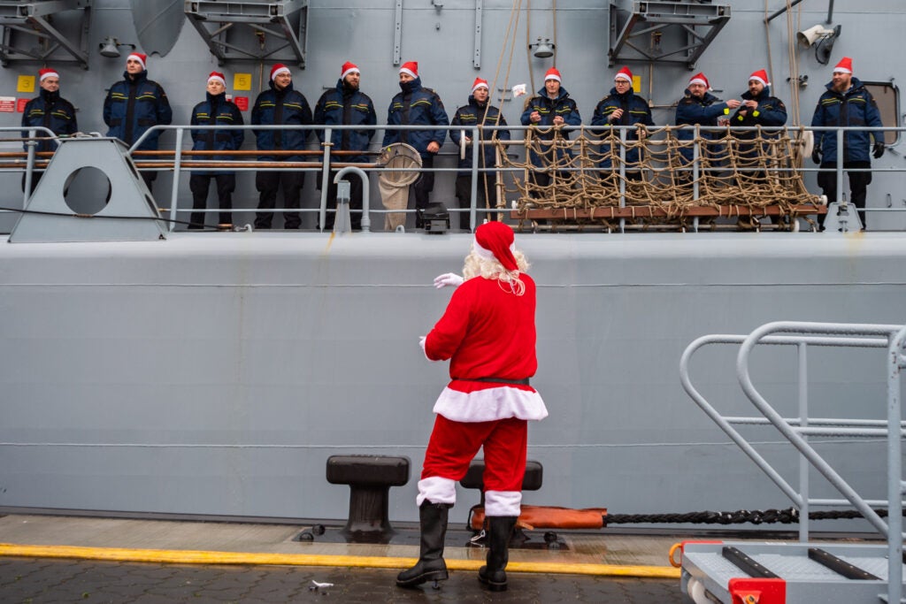 21 December 2018, Lower Saxony, Wilhelmshaven: During the docking manoeuvre of the frigate "Lübeck" a Santa Claus stands on the pier and throws sweets to the crew. After sea surveillance in the Mediterranean Sea, the ship returns to its home base in Wilhelmshaven. Photo: Mohssen Assanimoghaddam/dpa (Photo by Mohssen Assanimoghaddam/picture alliance via Getty Images)