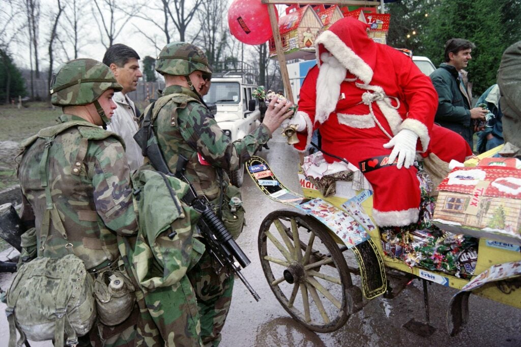 US NATO troopers receive chocolate and sweets from the Santa Claus who pays a visit to Tuzla airbase on December 25, 1995. The base is the home and headquarters of the NATO Task for Eagle. (Photo by Odd ANDERSEN / AFP) (Photo by ODD ANDERSEN/AFP via Getty Images)
