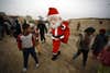 An Iraqi odontology student dressed in a Santa Claus outfit distribute gifts to impoverished children outside their shanty home in the Iraqi holy Shiite city of Najaf on December 25, 2016 / AFP / Haidar HAMDANI        (Photo credit should read HAIDAR HAMDANI/AFP via Getty Images)