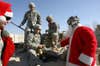 US soldiers dressed as Santa Claus hand candies to fellow soldiers at the Hammer base in southern Baghdad on Christmas eve, 24 December 2007. Christians around the world will celebrate Christmas tomorrow marking the birth of Jesus Christ. AFP PHOTO / ALI AL-SAADI (Photo credit should read ALI AL-SAADI/AFP via Getty Images)