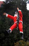 A Colombian soldier fancy dressed as Santa Claus rappels down from a Blackhawk military helicopter on December 17, 2008, in Medellin, Antioquia department, Colombia. AFP PHOTO/Raul ARBOLEDA (Photo credit should read RAUL ARBOLEDA/AFP via Getty Images)
