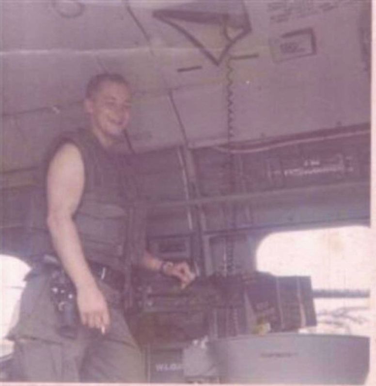 Ron Winter standing next to a .50 caliber machine gun on a CH-46D helicopter during the Vietnam War.