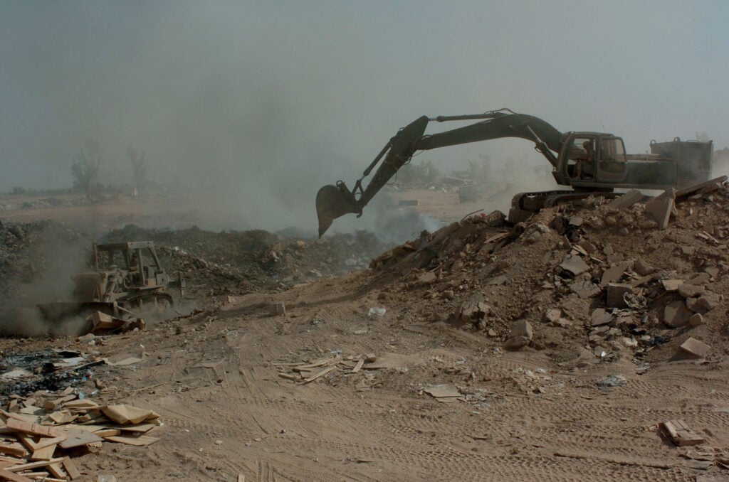 (LOGISTICS SUPPORT AREA ANACONDA, Balad, Iraq) - Soldiers from the 84th Combat Engineer Battalion use a bulldozer and excavator to manuever trash and other burnable items around in the burn pit at the landfill here. The bulldozer is primarily used to keep refuse constantly burning, and the excavator to push dirt over chutes to make the land useable in the future. 
-- IPTC Data ------------------
Position: 28th Public Affairs Detachment