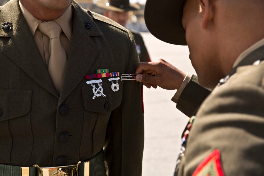 U.S. Marine Corps Gunnery Sgt. Miguel Cortes, an instructor for Drill Instructor School, Marine Corps Recruit Depot (MCRD) San Diego, measures a student's pistol badge spacing at MCRD San Diego, Calif., Feb. 26, 2016. Cortes ensured that the student's uniform was within regulations. (U.S. Marine Corps photo by Lance Cpl. Robert G. Gavaldon/Released)
