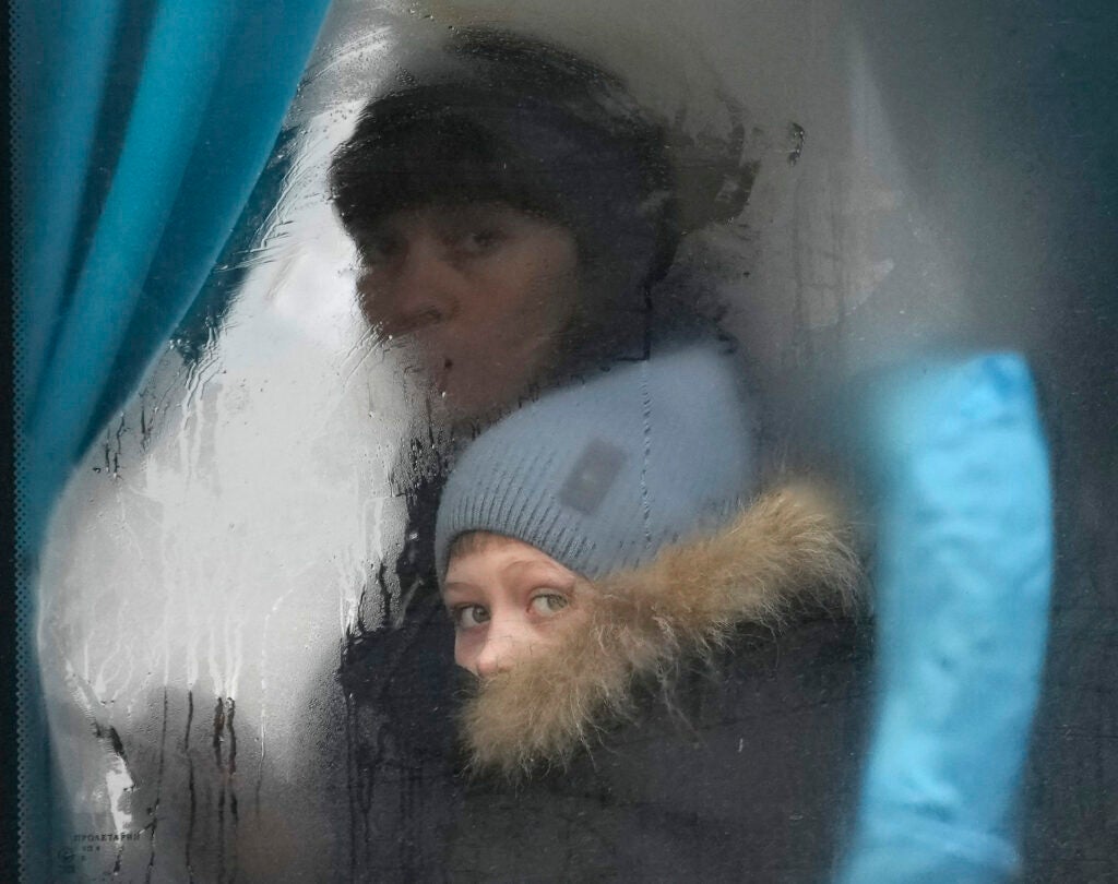 A woman and child peer out of the window of a bus as they leave Sievierodonetsk, the Luhansk region, eastern Ukraine, Thursday, Feb. 24, 2022. Russian President Vladimir Putin on Thursday announced a military operation in Ukraine and warned other countries that any attempt to interfere with the Russian action would lead to "consequences you have never seen." (AP Photo/Vadim Ghirda)