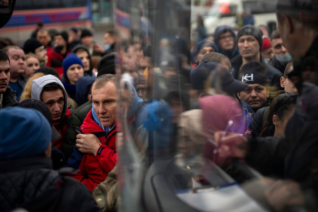 People struggle to get on a bus as they try to leave Kyiv, Ukraine, Thursday, Feb. 24, 2022. Russia launched a wide-ranging attack on Ukraine on Thursday, hitting cities and bases with airstrikes or shelling, as civilians piled into trains and cars to flee. (AP Photo/Emilio Morenatti)
