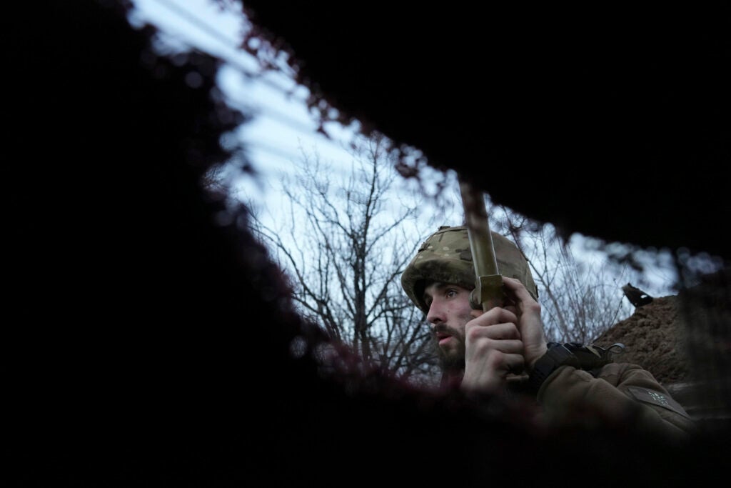 A Ukrainian service member listens to artillery shots standing in a trench on a position at the line of separation between Ukraine-held territory and rebel-held territory near Zolote, Ukraine, late Saturday, Feb. 19, 2022. (AP Photo/Evgeniy Maloletka)