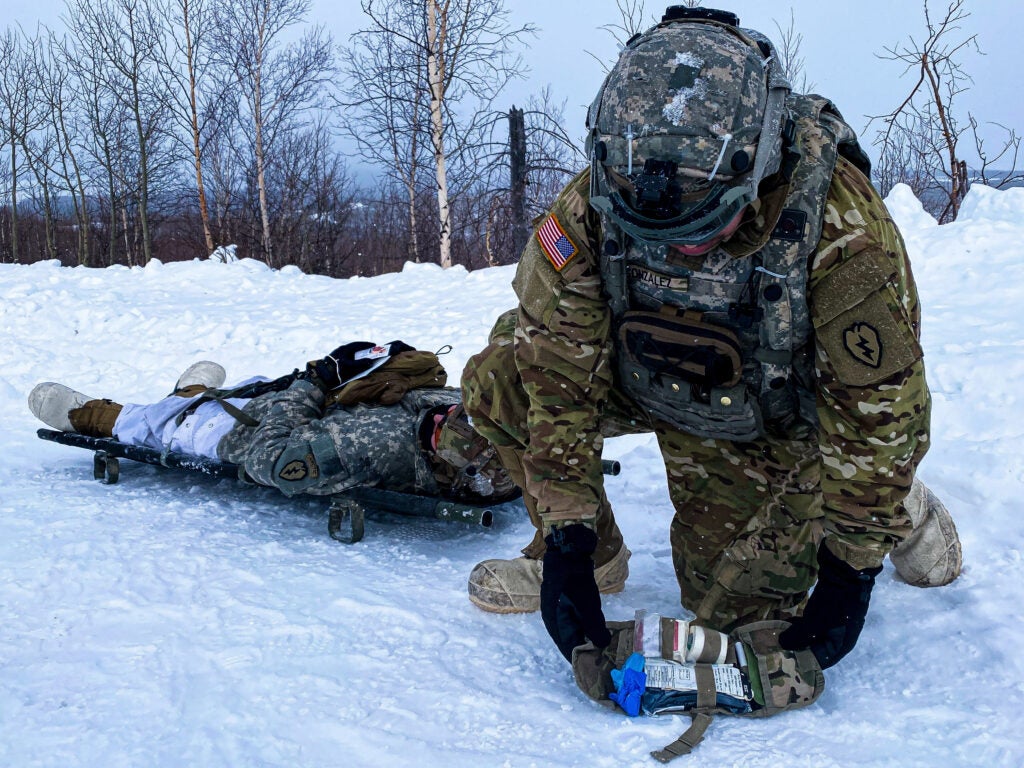 In a simulated casualty scenario, U.S. Army Spc. Andrei Gonzalez, assigned to 1st Battalion, 25th Infantry Regiment uses an Extreme Cold Weather Experimental Individual First Aid Kit Prototype to render aid to Cpl. Cole Clair, a Soldier in his unit, during a Joint Pacific Multinational Readiness Center 22-02 live fire exercise near Ft. Greely on March 19, 2022. 