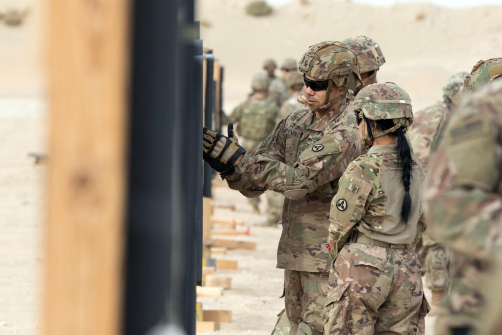 Sgt. Maj. Jeovannie Melendez, the chief signal noncommissioned officer for the Fort Bragg, N.C., based 3rd Expeditionary Sustainment Command goes over a target with Cpl. Leslie M. Cardona during an M4 qualification range at Camp Buehring, Kuwait, on Dec. 2, 2021. The “Spears Ready” Soldiers have been deployed since August staffing the 1st Theater Sustainment Command operational command post.