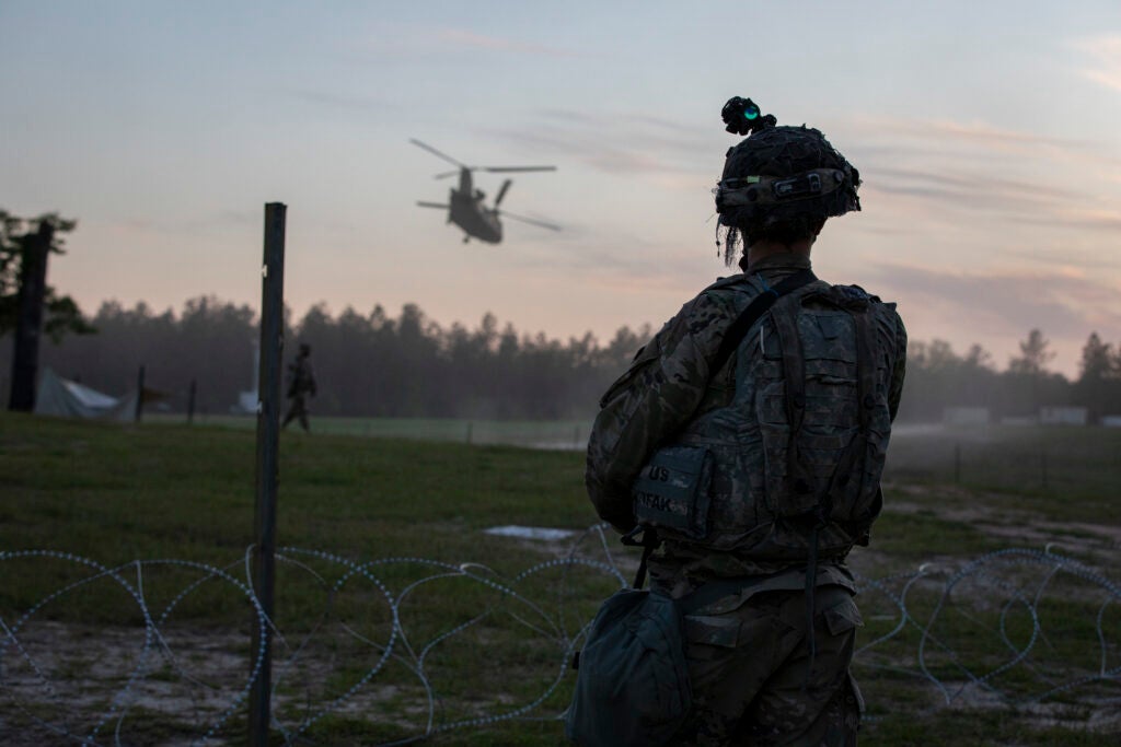 A U.S. Army Soldier assigned to brigade Headquarters and Headquarters Company, 317th Brigade Engineer Battalion, 3rd Brigade Combat Team, 10th Mountain Division, on brigade tactical operations center entry control point guard watches a CH-47 Chinook helicopter as it departs the area of operations at Peason Ridge, Fort Polk, Louisiana, April 10, 2021. The brigade is currently participating Joint Readiness Training Center rotation 21-06. (U.S. Army photo by Staff Sgt. Ashley M. Morris)