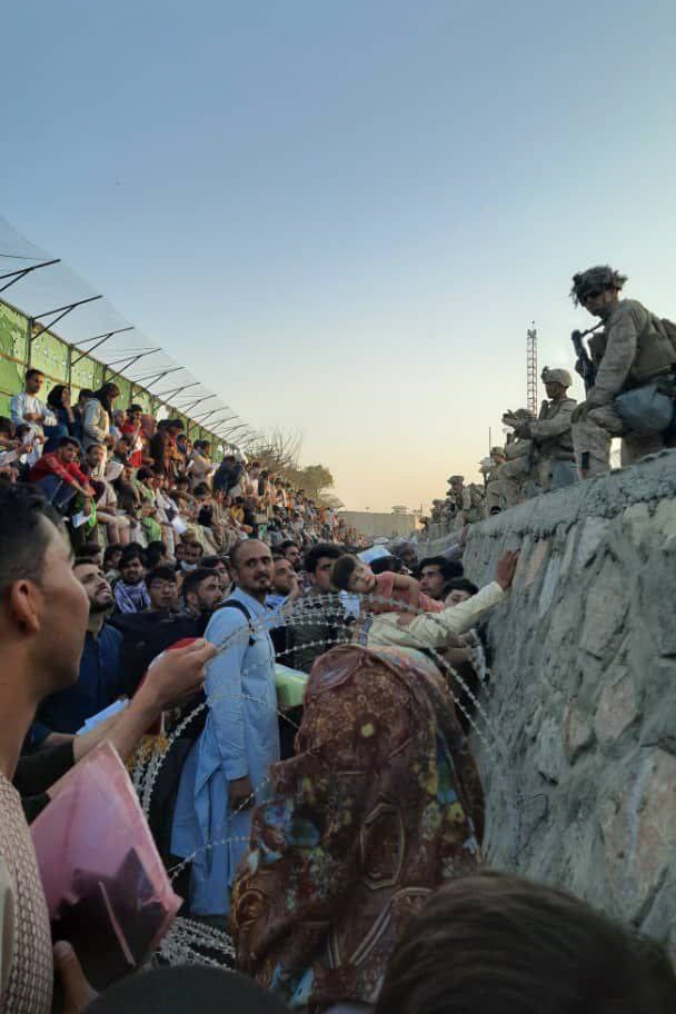 Afghans stand in the sewage ditch outside Abbey Gate as they attempt to show documents to Marines processing evacuees on Aug. 25. (Mirzahussain Sadid for Alive in Afghanistan) 