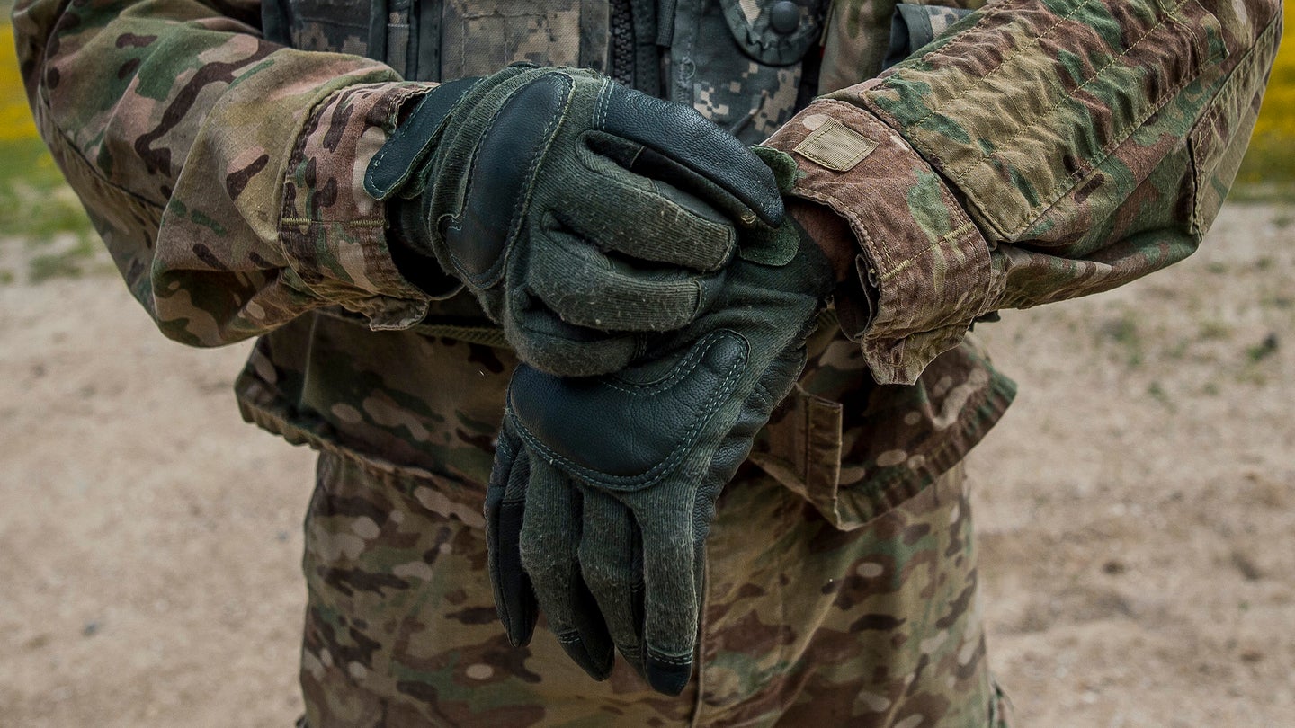 A U.S. Army Reserve Soldiers puts on his gloves before the start of a rifle zero range during the 200th Military Police Command's Best Warrior Competition held at Fort Hunter Liggett, California, April 16, 2018. 