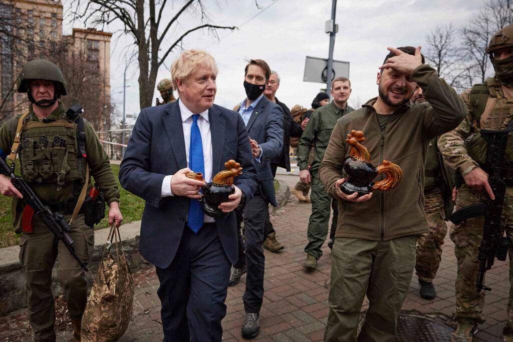 In this image provided by the Ukrainian Presidential Press Office, Ukrainian President Volodymyr Zelenskyy, right, and Britain's Prime Minister Boris Johnson, center left, hold souvenirs presented by a civilian woman in Kyiv, Ukraine, Saturday, April 9, 2022. (Ukrainian Presidential Press Office via AP)