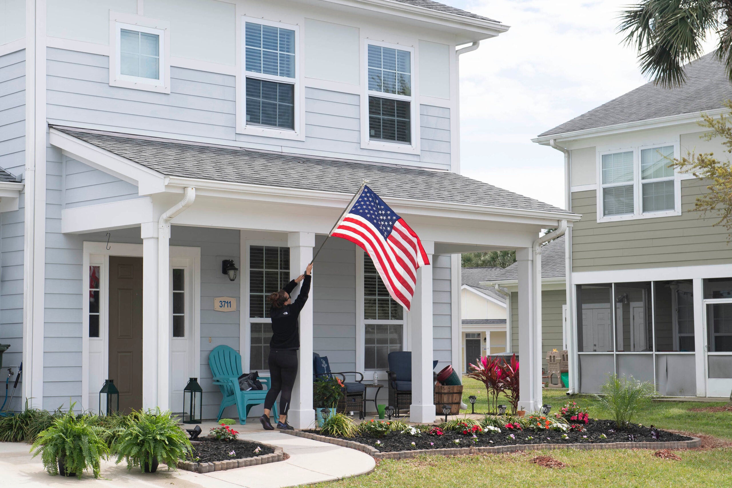 190318-N-DW182-182 
MAYPORT, Fla. (March 18, 2019) Crista Gyates, a resident at Balfour Beatty Housing, raises the American flag at her home in Bennett Shores East, an on-base military housing community at Naval Station Mayport. (U.S. Navy photo by Mass Communication Specialist 2nd Class Devin Bowser/Released)