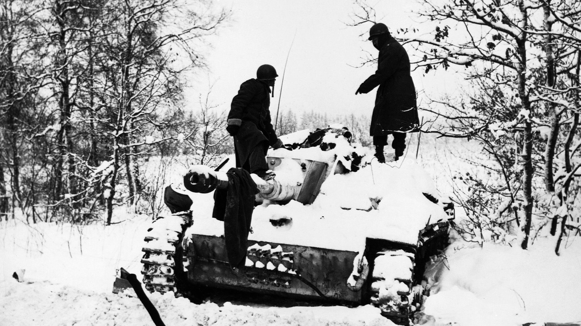Two soldiers look at a dead crewman on a snow-covered German tank during the Battle of the Bulge. St. Vith, Belgium. | Location: St. Vith, Belgium. (Photo by © CORBIS/Corbis via Getty Images)