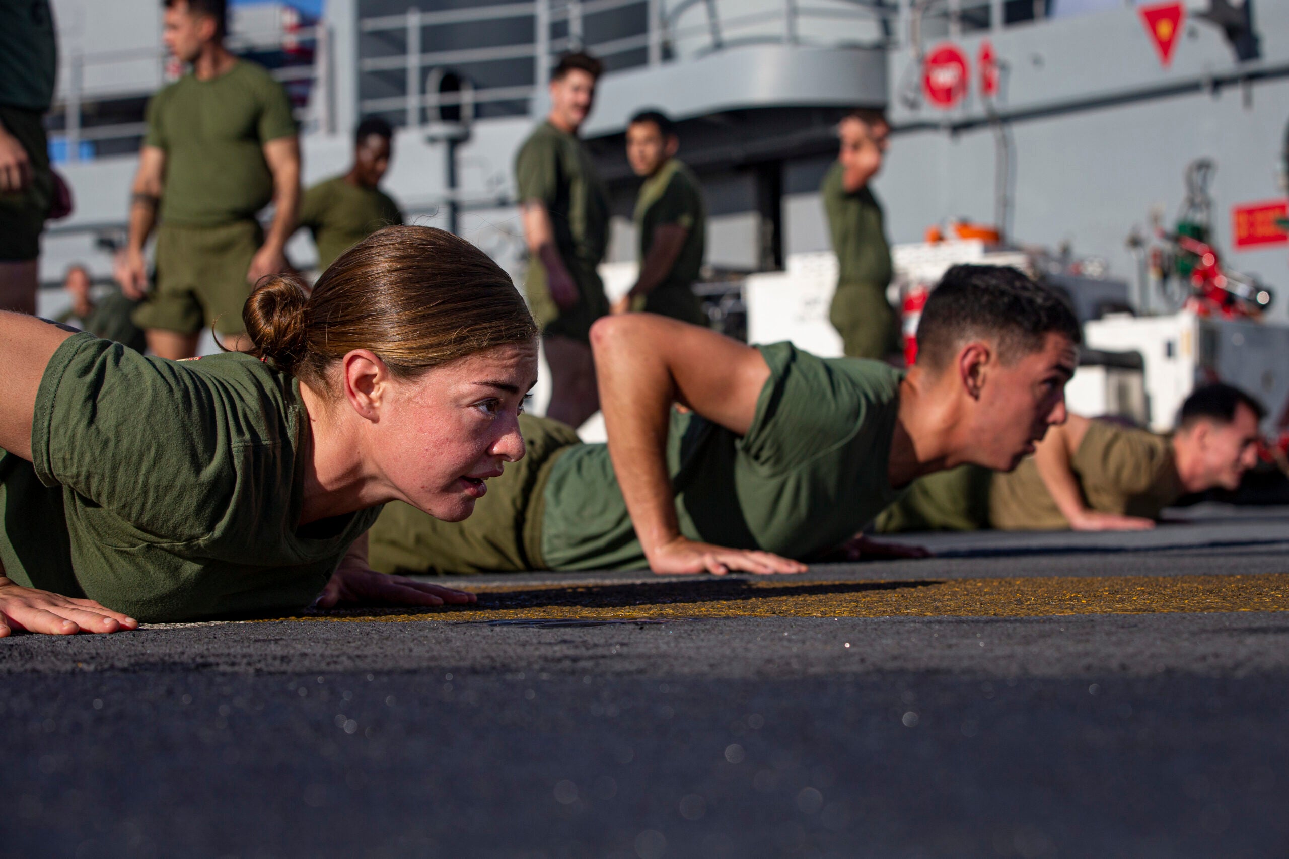 U.S. Marine Corps Lance Cpl. Claudia Murphy, a mortarman with Battalion Landing Team (BLT) 3/5, 31st Marine Expeditionary Unit (MEU), prepares for a sprint during unit physical training on the flight deck aboard amphibious assault ship USS America (LHA 6), in the Pacific Ocean, July 10, 2021. The 31st MEU is operating aboard ships of the America Expeditionary Strike Group in the 7th fleet area of operations to enhance interoperability with allies and partners and serve as a ready response force to defend peace and stability in the Indo-Pacific region. Murphy is a native of St. Albans Vermont. (U.S. Marine Corps photo by Cpl. Karis Mattingly)