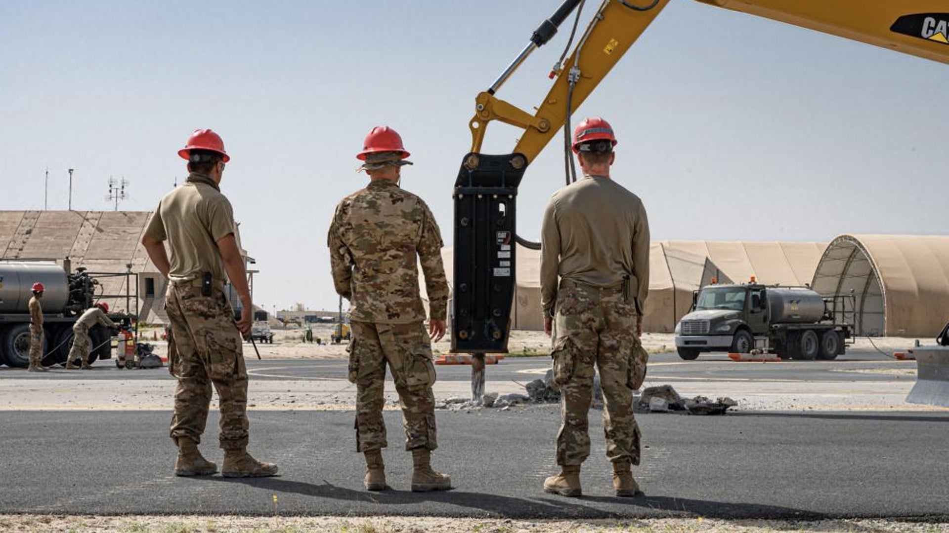 U.S. Air Force Tech. Sgt. Julio Duran Sangabriel, left, Master Sgt. Michael Rael, project manager, and 1st Lt. Kyle Price, a design engineer, with the 557th Expeditionary Rapid Engineer Deployable Heavy Operational Repair Squadron Engineer Squadron, or RED HORSE, oversee the drilling of concrete of a taxiway at Ali Al Salem Air Base, Kuwait, Feb. 22, 2022 (Senior Airman Natalie Filzen / U.S. Air Force)