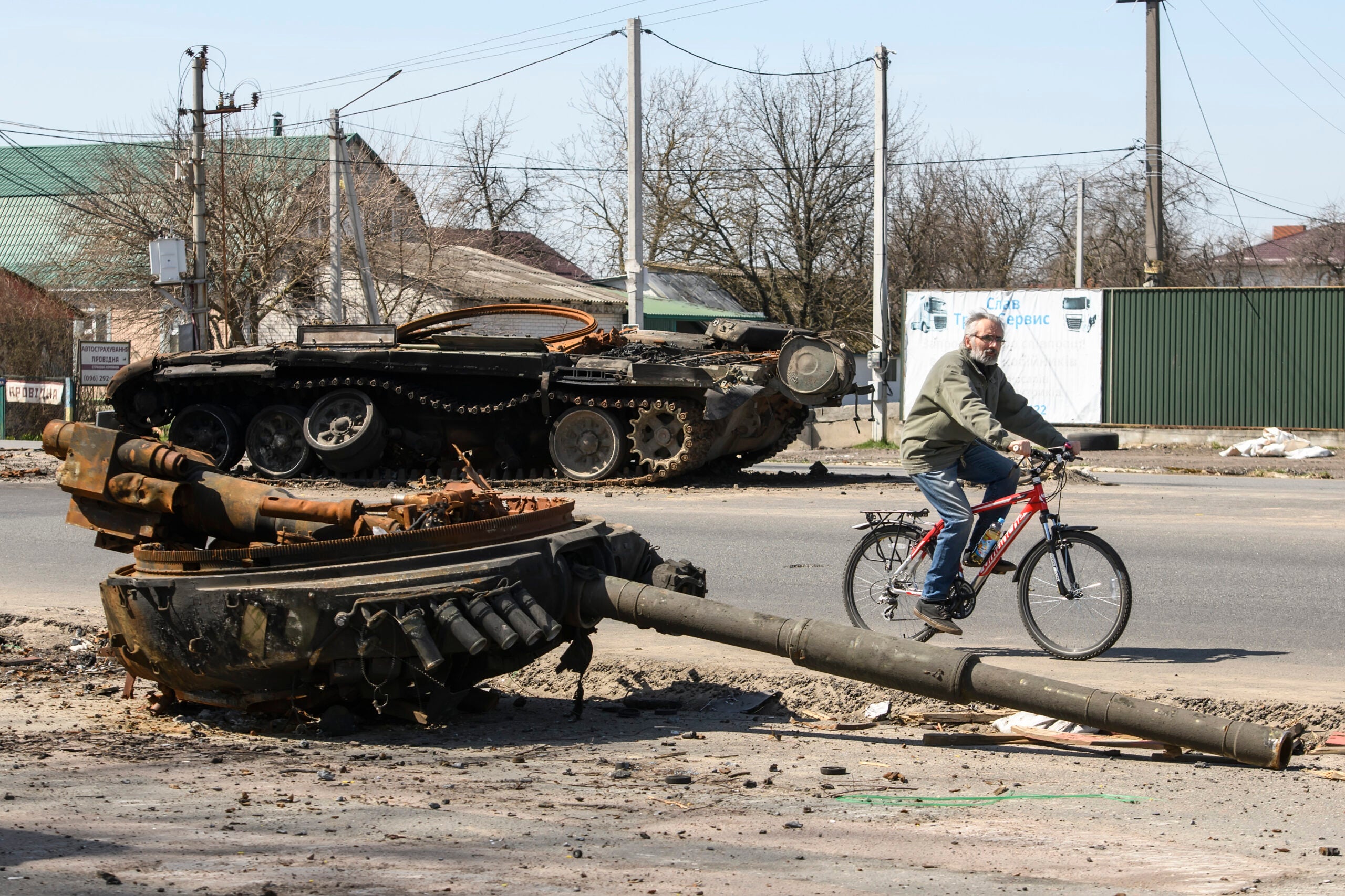 A man ride bike near Destroyed Russian military tank near Brovary, Kyiv area, Ukraine, 15 April 2022 (Photo by Maxym Marusenko/NurPhoto via Getty Images)