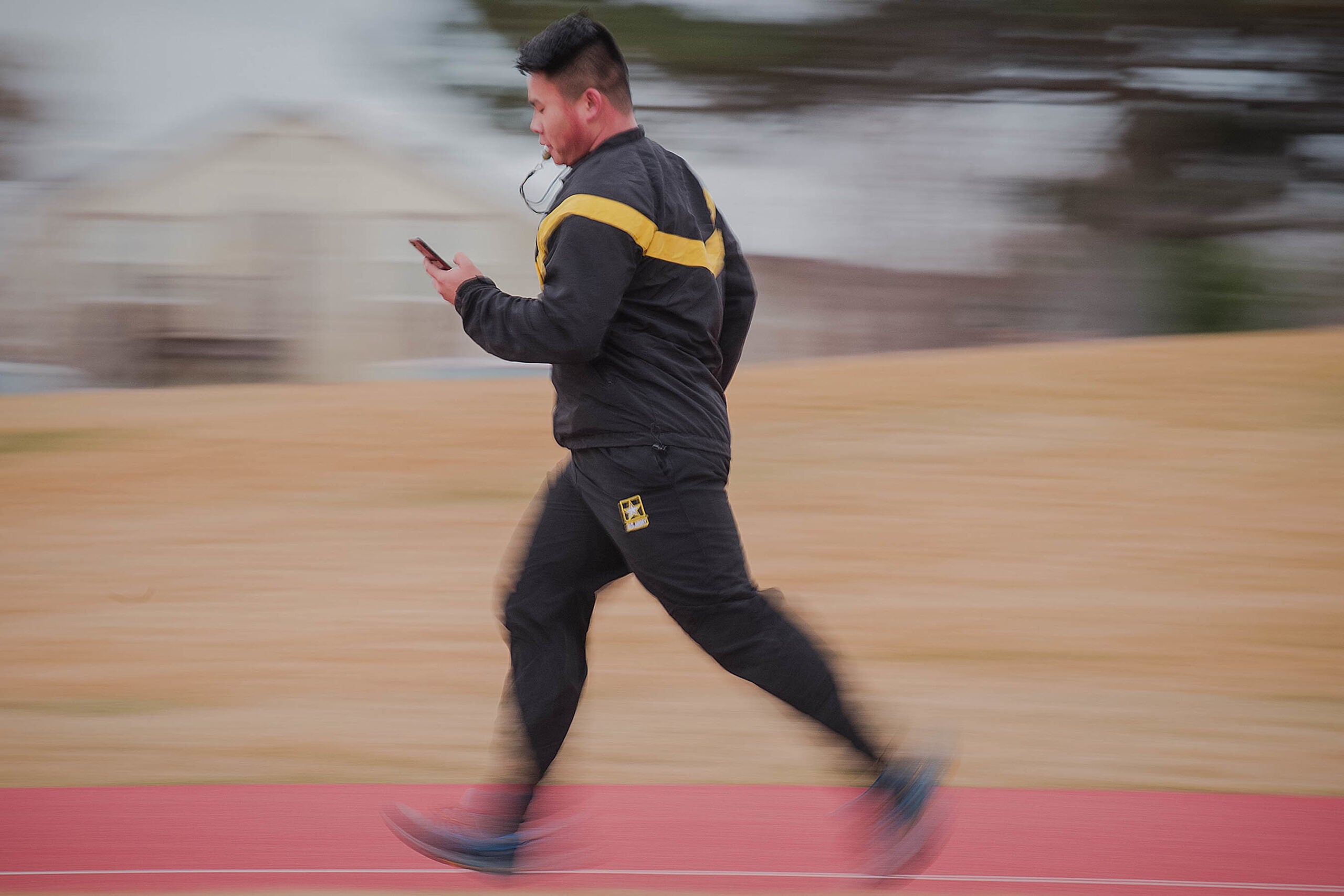 As class leader for the evening workout, Sgt. Lixing Dai monitors the time on his smartphone. Dai had the class sprinting, fast walking, then sprinting again in timed increments. Sgt. Dai monitored the time, blowing his whistle to begin or end each walk/run cycle.