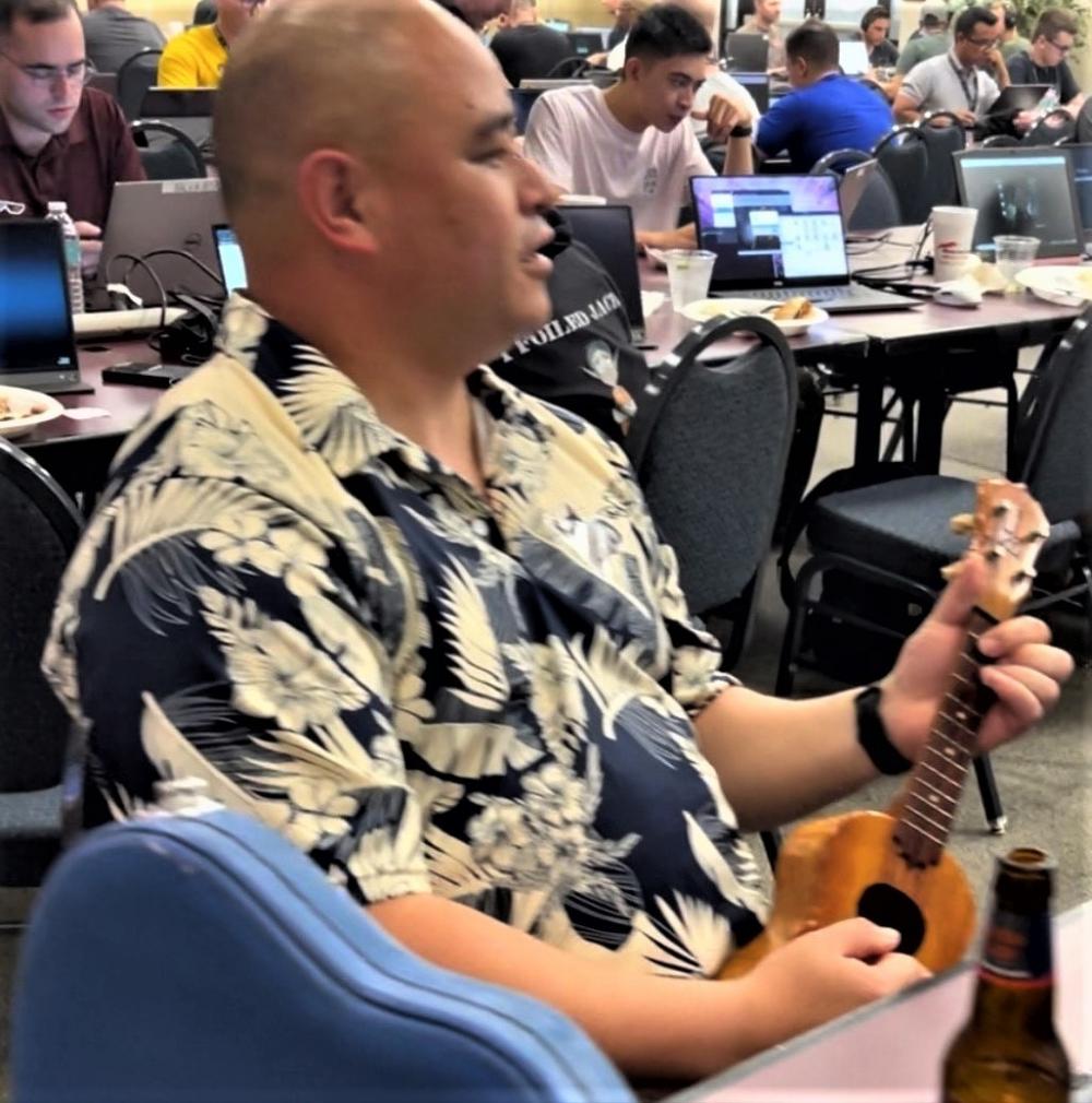 A Netwars competitor strums on his ukulele during Netwars. (Sgt. Trenton Fouche / U.S. Army)