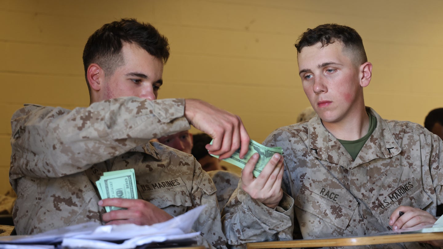 Two U.S. Marine finance technicians, both with 2d Landing Support Battalion, 2nd Marine Logistics Group, simulate an exchange during a disbursement exercise, Camp Lejeune, N.C., Apr. 6, 2022. (Lance Cpl. Adam Scalin/U.S. Marine Corps)