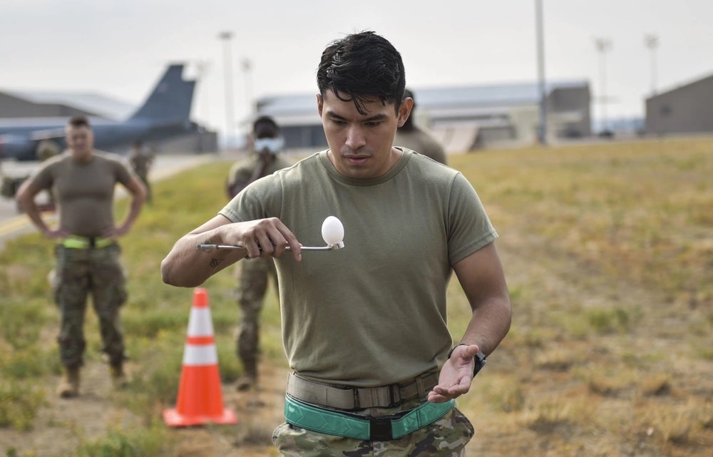 U.S. Air Force Senior Airman Joel N. Perez, 92nd Aircraft Maintenance Squadron Communication Navigation Mission Systems Journeyman, carries an egg on a wrench during an egg relay race at the Maintenance Olympics event at Fairchild Air Force Base, Washington, Aug. 20, 2021. (Staff Sgt. Dustin Mullen / U.S. Air Force)