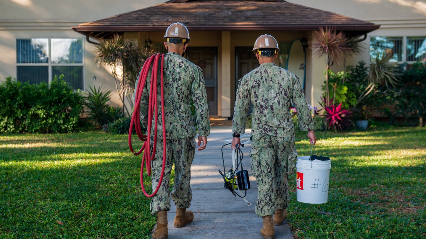 Two sailors assigned to Construction Battalion Maintenance Unit (CBMU) 303, walk toward a Joint Base Pearl Harbor-Hickam (JBPHH) resident’s home to conduct a field team home visit in February 2022. (Mass Communication Specialist 2nd Class Mar’Queon A. D. Tramble/U.S. Navy)
