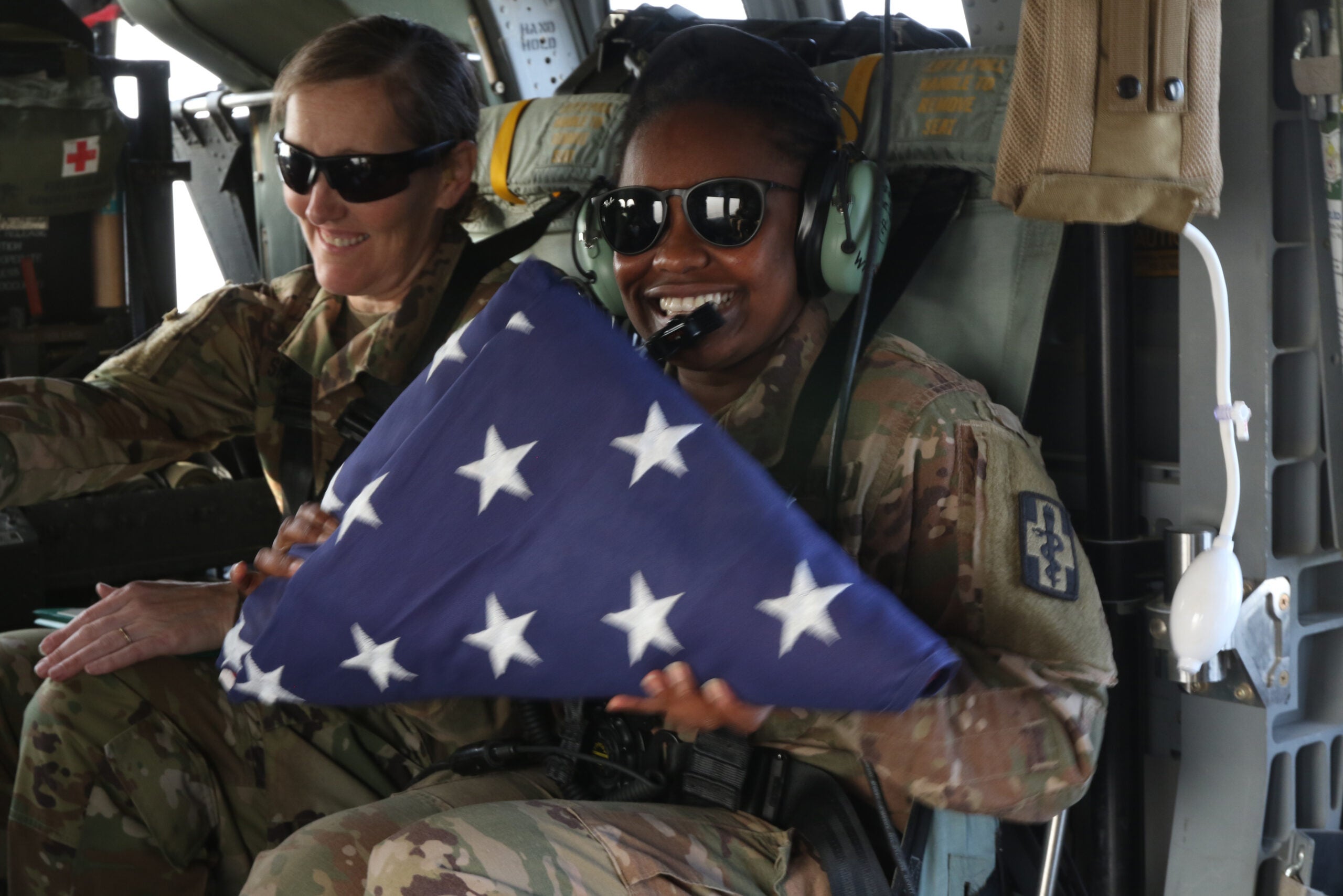 Sgt. Sylvia Mwangi, 452nd Combat Support Hospital, holds the American flag following an airborne reenlistment ceremony over Camp Arifjan, Kuwait, Dec. 28, 2018. (U.S. Army photo by Staff Sgt. Veronica McNabb)