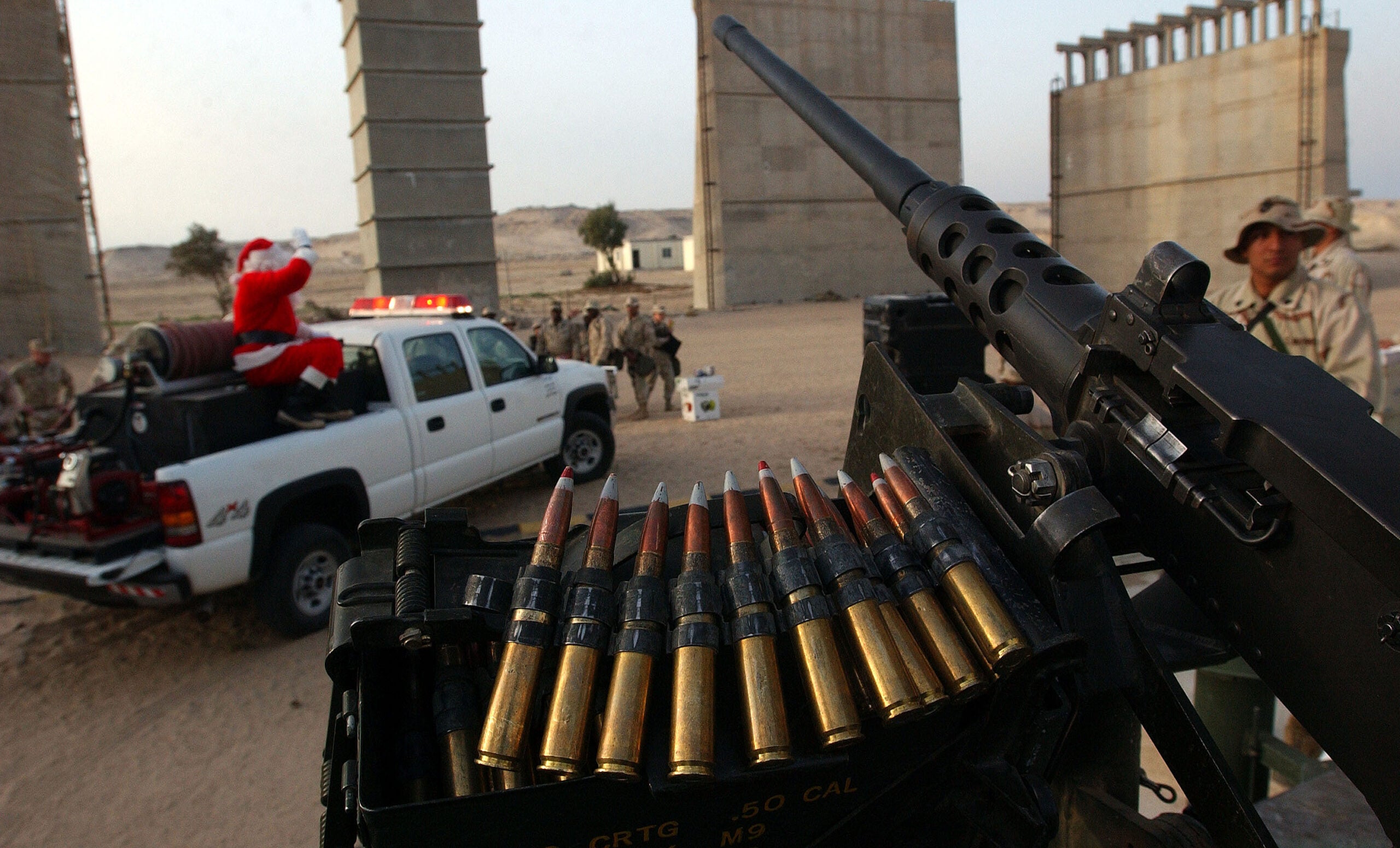 CAMP COMMANDO, KUWAIT - DECEMBER 24:  Santa Claus travels under the cover of a 50 caliber machine gun after passing out gifts to several hundred U.S. Marines of the 1st Marine Expeditionary Force stationed at Camp Commando in the Kuwaiti Desert during a December 24, 2002 Christmas Eve formation there. Santa passed out gifts from Kuwaiti residents and soldiers sang Christmas carols to celebrate the holiday season.  (Photo by Scott Nelson/Getty Images)