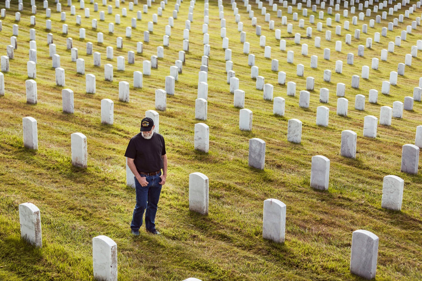 Bearded Vietnam veteran standing, pacing and walking in a United States military cemetery.