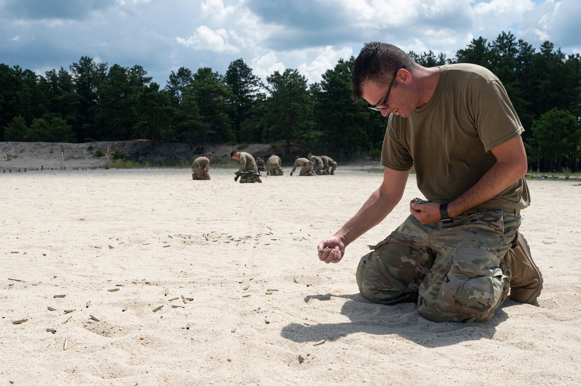 A student picks up brass after completing weapons training during Fieldcraft Hostile on Joint Base McGuire-Dix-Lakehurst, New Jersey, Aug. 8, 2022. FCH is a pre-deployment course directed by the 421st Combat Training Squadron, that teaches basic combat skills to over 5,000 U.S. Air Force, Joint and NATO personnel annually. (U.S. Air Force photo by Staff Sgt. Jake Carter)
