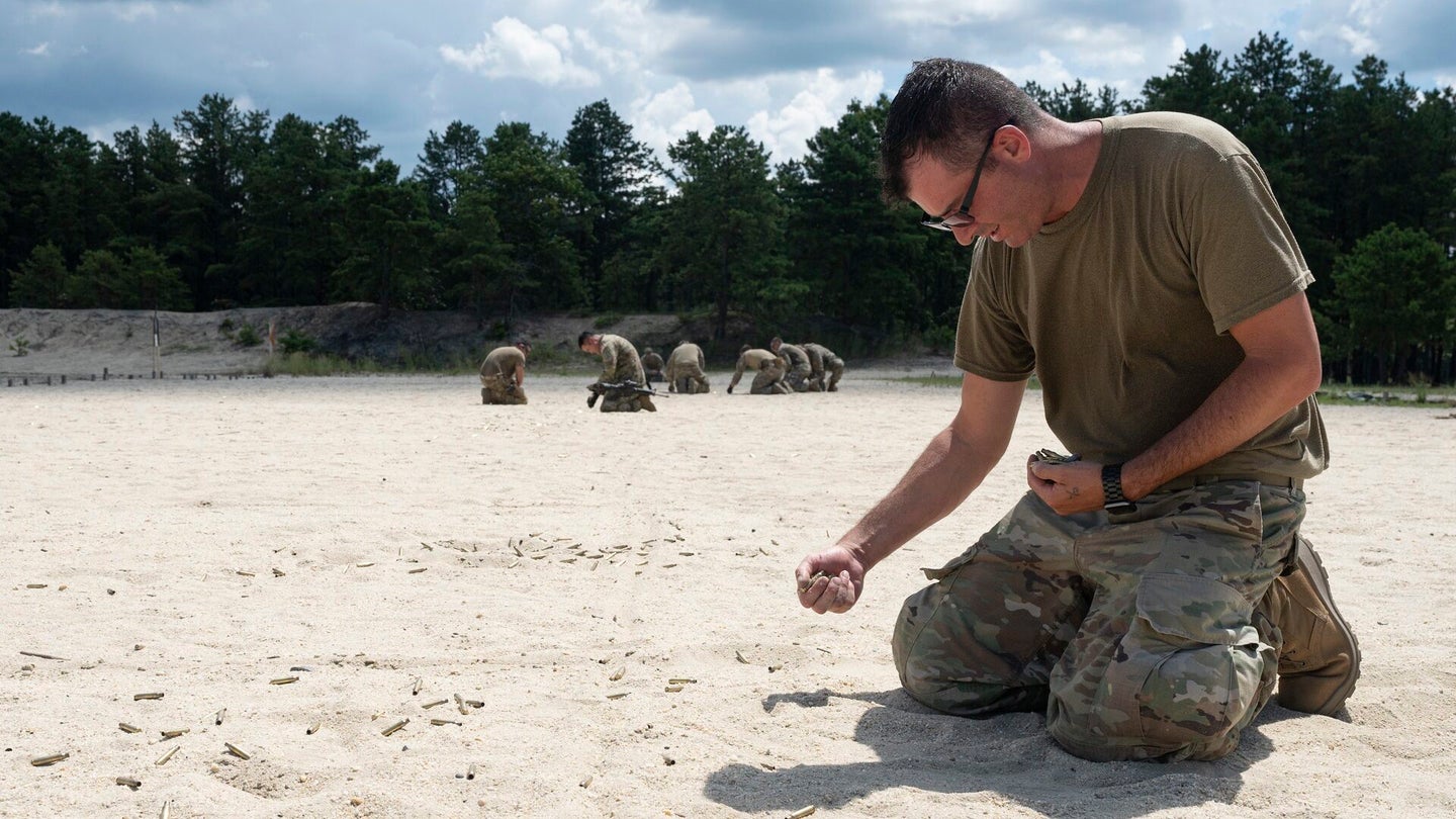 A student picks up brass after completing weapons training during Fieldcraft Hostile on Joint Base McGuire-Dix-Lakehurst, New Jersey, Aug. 8, 2022. (Staff Sgt. Jake Carter/U.S. Air Force)