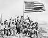 United States Marines pose on top of Mount Suribachi on the island of Iwo Jima with the American flag.
