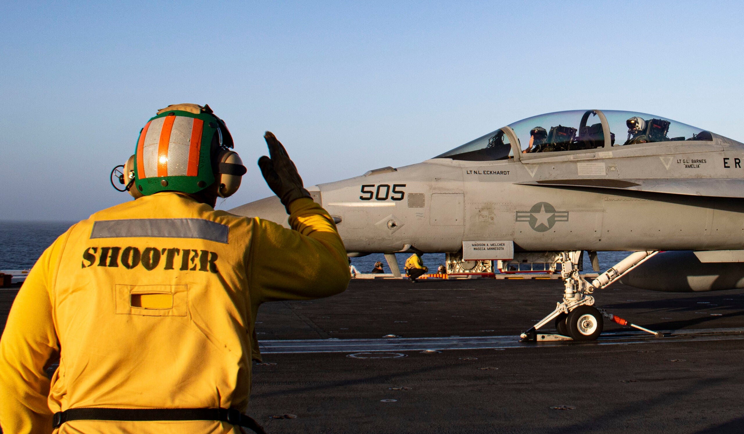 220614-N-MJ302-1170 PACIFIC OCEAN (June 14, 2022) A Shooter salutes the pilot of an E/A-18G Growler, from the “Cougars” of Electronic Attack Squadron (VAQ) 139, on the flight deck of the aircraft carrier USS Nimitz (CVN 68). Nimitz is underway in the U.S. 3rd Fleet area of operations. (U.S. Navy photo by Mass Communication Specialist 3rd Class David Rowe)