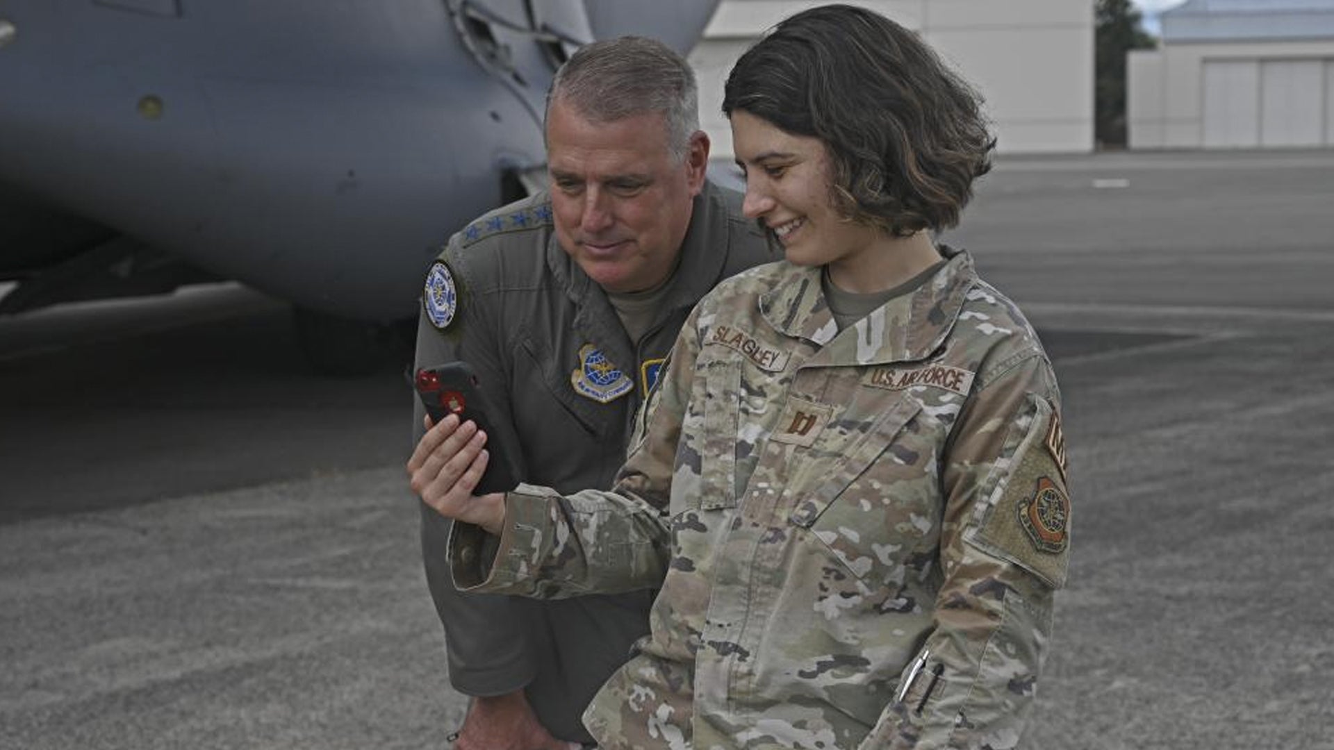 U.S. Air Force Gen. Mike Minihan, left, Air Mobility Command commander, and Capt. Madeline Slagley, 62nd Maintenance Squadron officer in charge, FaceTime Slagley’s family at Joint Base Lewis-McChord, Washington, July 7, 2022. Minihan coined Slagley as a star performer during his visit to JBLM. (Senior Airman Callie Norton/U.S. Air Force)