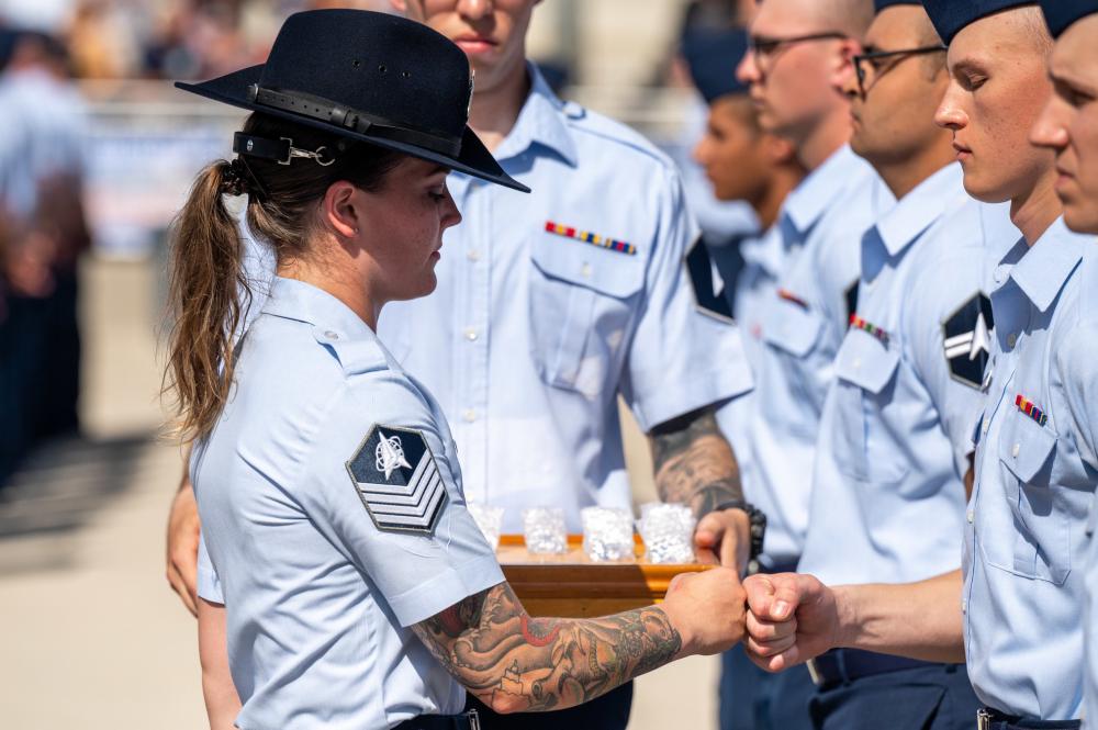 U.S. Space Force Tech Sgt. Michelle Holt, Military Training Instructor, 1st Delta Operations Squadron, bumps fists with a basic military training Guardian graduate during a coining ceremony on June 22, 2022, at the Pfingston Reception Center on Joint Base San Antonio-Lackland, Texas. (Ethan Johnson/U.S. Space Force)