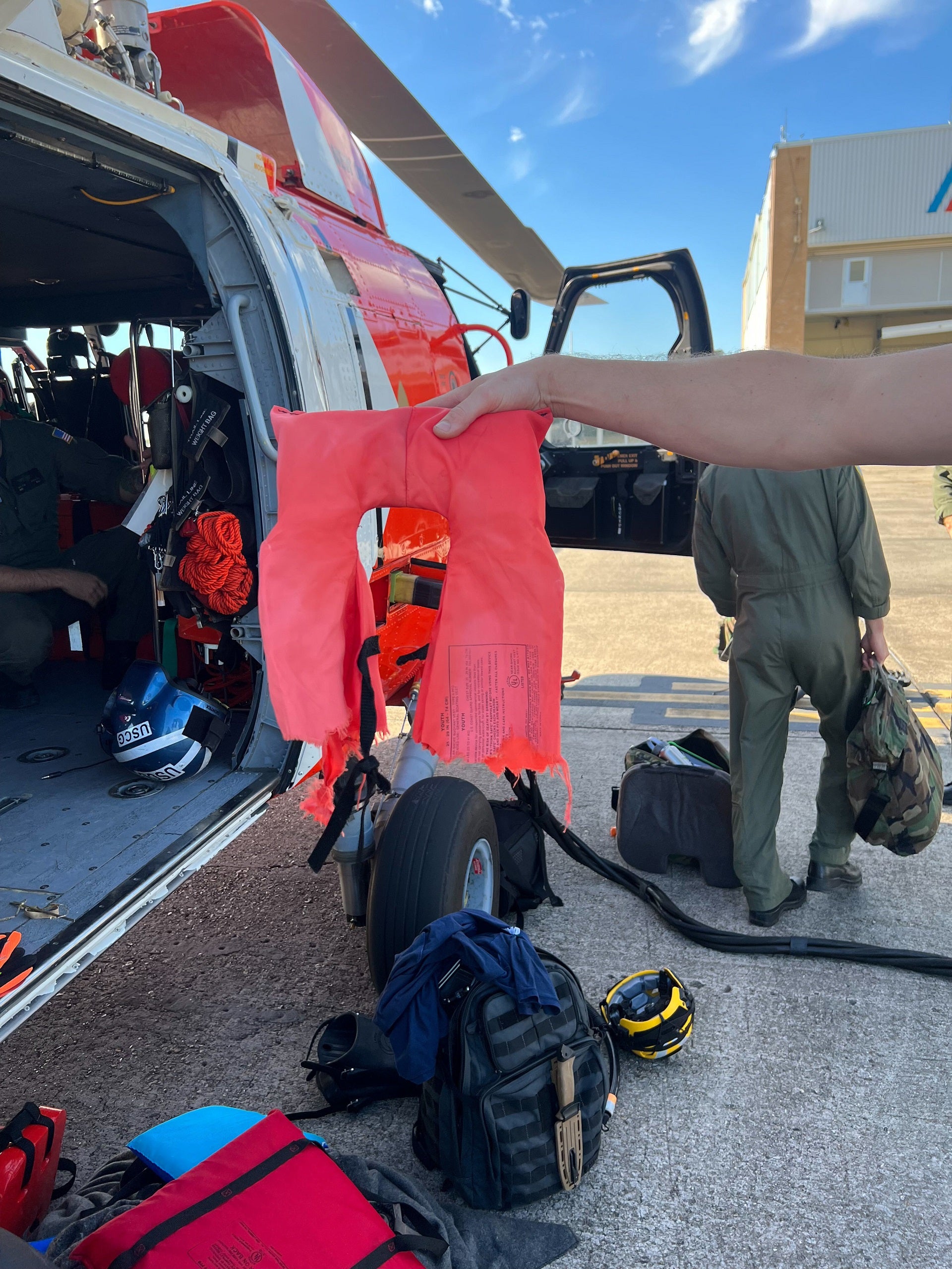 A Coast Guard Air Station New Orleans aircrew member holds up a torn life jacket from a recent rescue off the coast of Empire, Louisiana, Oct. 9, 2022. One of the boater's life jackets was torn due to a shark attack. (U.S. Coast Guard photo by Coast Guard Air Station New Orleans)