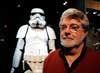 FILE - In this Oct. 22, 2005 file photo, filmmaker George Lucas poses in front of a Stormtrooper exhibit at the Museum of Science in Boston, prior to the opening of "Star Wars: Where Science Meets Imagination." Lucas is visiting a galaxy on the edge of downtown Los Angeles to break ground on his $1.5 billion Lucas Museum of Narrative Art. The “Star Wars” creator and his wife will be joined Wednesday morning, March 14, 2018, by several city and county officials to ceremoniously begin work on turning a section of Exposition Park into the new museum.  (AP Photo/Winslow Townson, File)