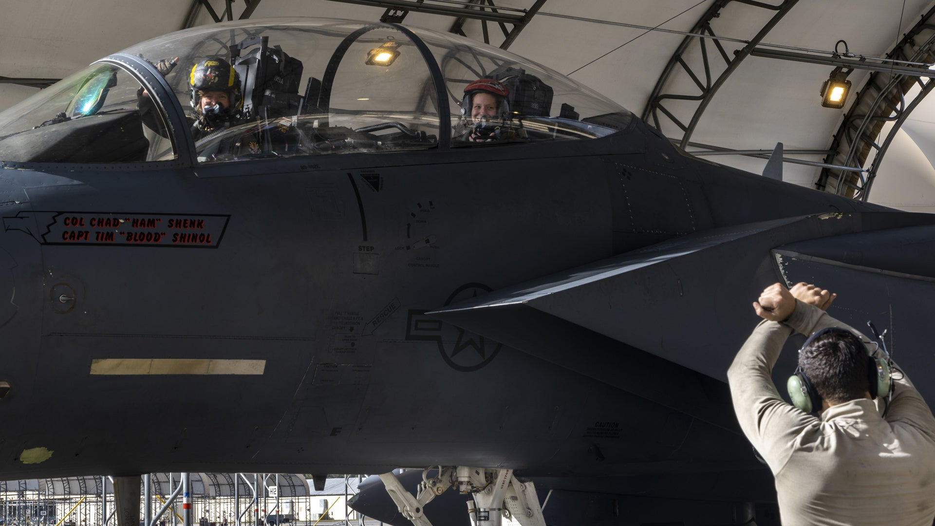 An airman assigned to the 4th Fighter Wing marshals an F-15E Strike Eagle into a hangar after taking part in a fini-flight at Seymour Johnson Air Force Base, North Carolina, Nov. 9, 2022. The fini-flight, which included an all-mom aircrew, was held for Maj. Tiffany McElroy, 333rd Fighter Squadron instructor weapons systems officer. (Senior Airman Kylie Barrow/U.S. Air Force)