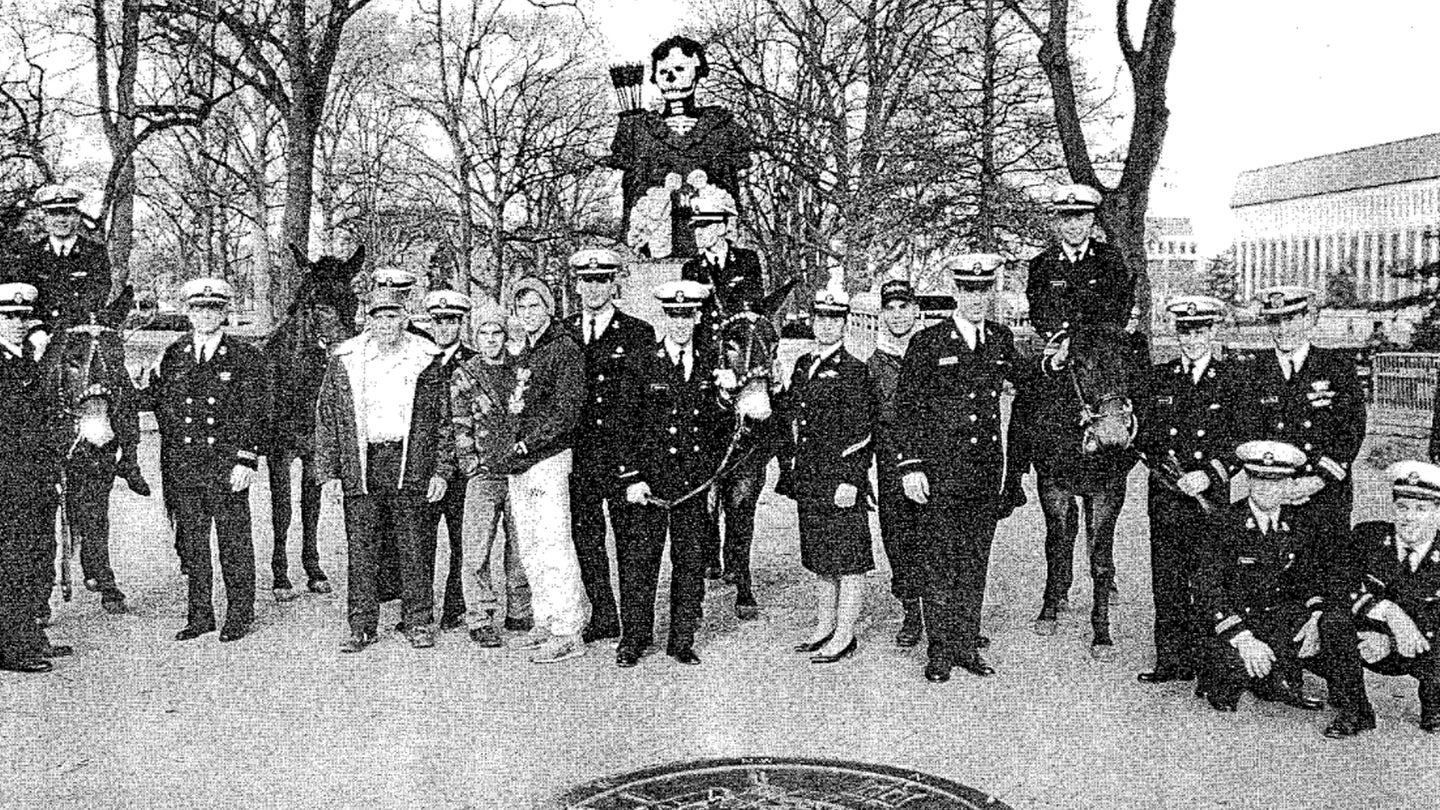 The U.S. Naval Academy midshipmen, advisors and a civilian mule farmer who infiltrated West Point and kidnapped their four mule mascots pose with their trophies at the Naval Academy in December 1991. (Screenshot via The LOG Magazine, U.S. Navy)