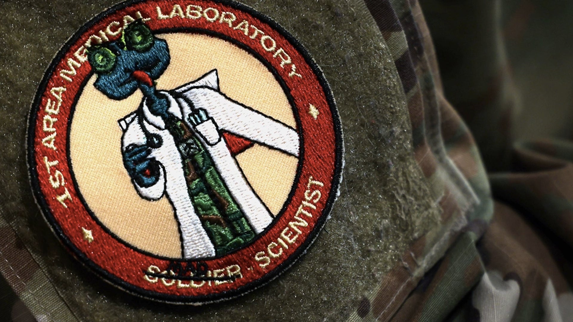 The print on the 1st Area Medical Laboratory's unit patch reads, “Mad Scientist,” and was on display during a change of command ceremony, which welcomed Col. Matthew Grieser as the new commander, July 23, 2021, at the Mallett Auditorium on Aberdeen Proving Ground, Maryland. The 1st AML is the U.S. Army’s only active duty deployable laboratory for theater level validation of Chemical, Biological, Radiological and Nuclear agents. (Marshall R. Mason/U.S. Army)