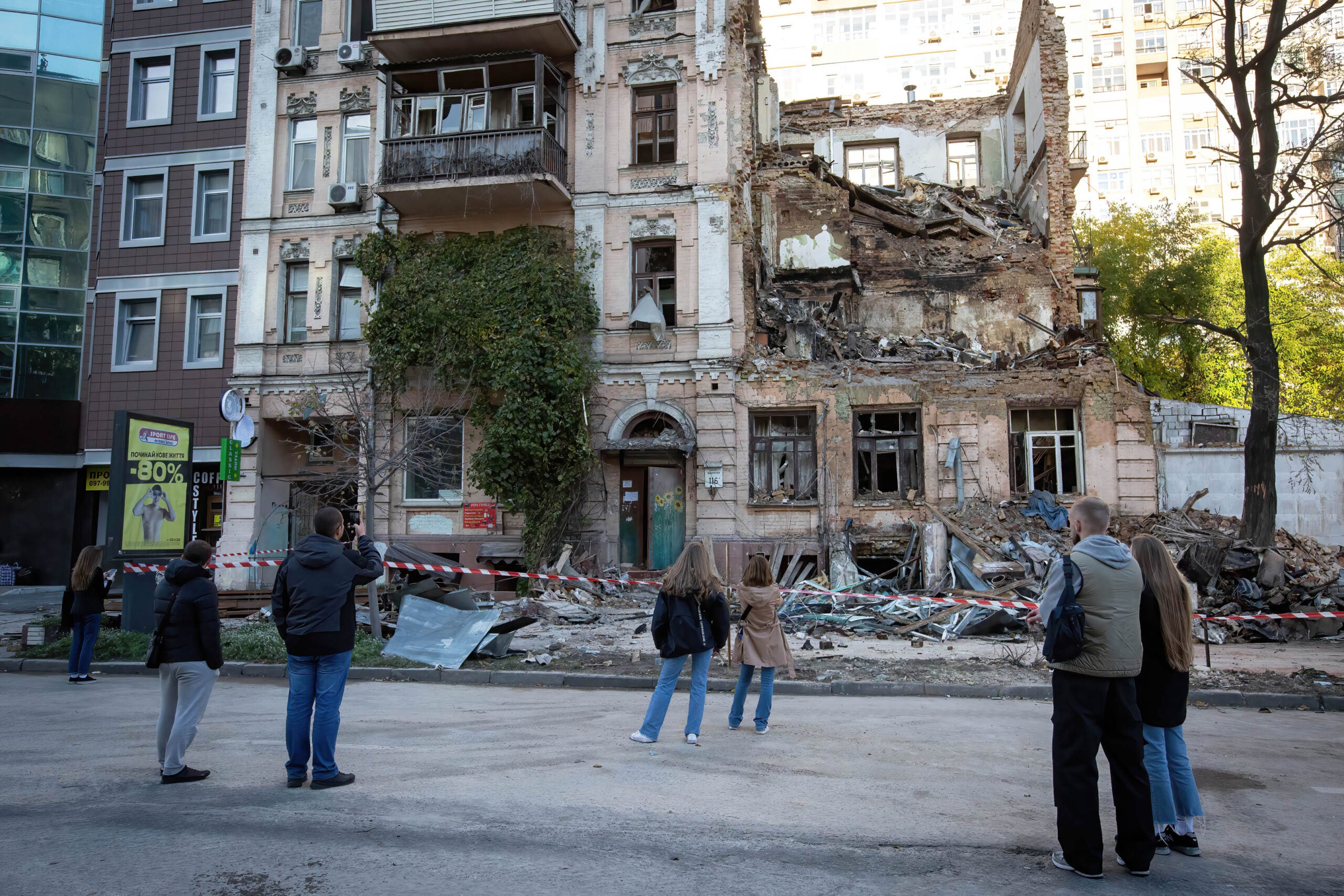 KYIV, UKRAINE - 2022/10/18: People look at the residential building destroyed by a Russian drone strike, which local authorities consider to be Iranian-made unmanned aerial vehicles (UAVs) Shahed-136, in central Kyiv. At least four people have been killed as a result of a drone attack on a residential building in Kyiv on the morning of October 17, 2022. (Photo by Oleksii Chumachenko/SOPA Images/LightRocket via Getty Images)